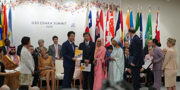 ADB President Mr. Takehiko Nakao (right) hands to Japan Prime Minister Mr. Shinzo Abe a report on an ADB Sri Lanka women’s entrepreneurship project during the Osaka G20 Summit.