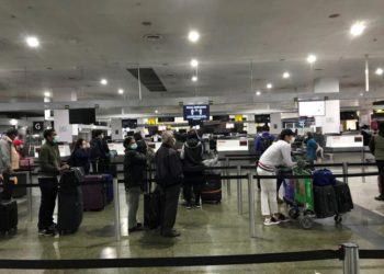 Passengers at Melbourne Airport observing social distancing while waiting to check-in for their flight home