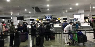Passengers at Melbourne Airport observing social distancing while waiting to check-in for their flight home