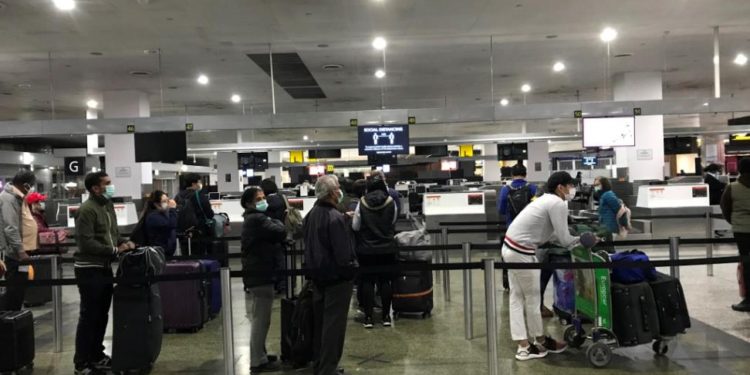 Passengers at Melbourne Airport observing social distancing while waiting to check-in for their flight home