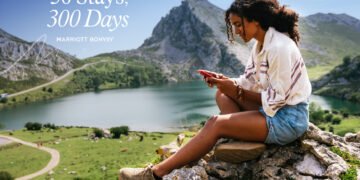 Happy brown skinned woman texting on the phone after a hike, a day in the mountain in the summit of Europe Peaks in Asturias, at Picos de Europa in Asturias of Spain